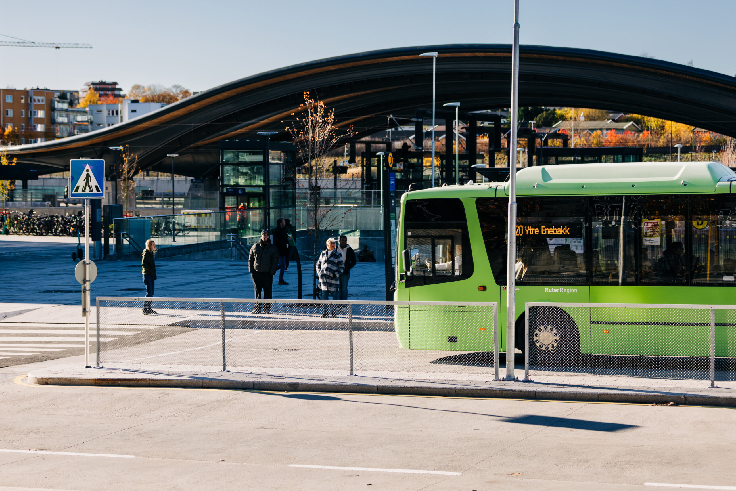En grønn Ruter regionbuss foran et knutepunkt for kollektivtransport.
