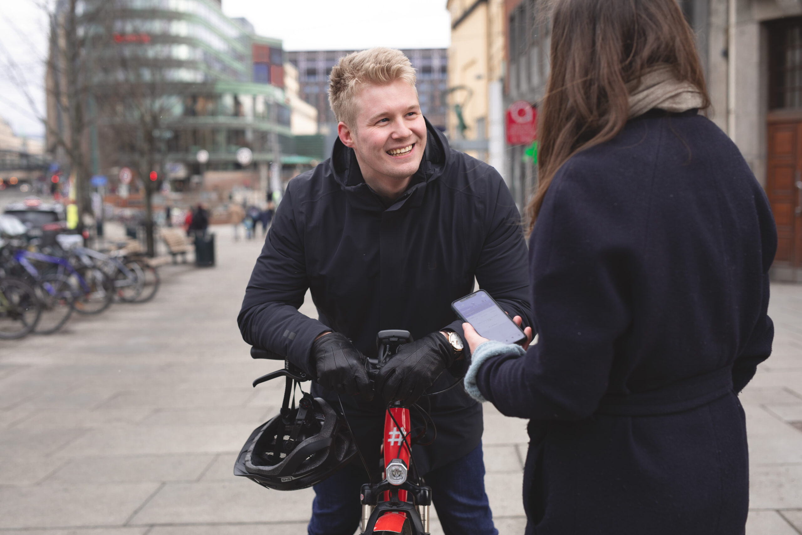 En mann på en Ruter-sykkel og en kvinne i prat om Ruter-appen på Jernbanetorget.