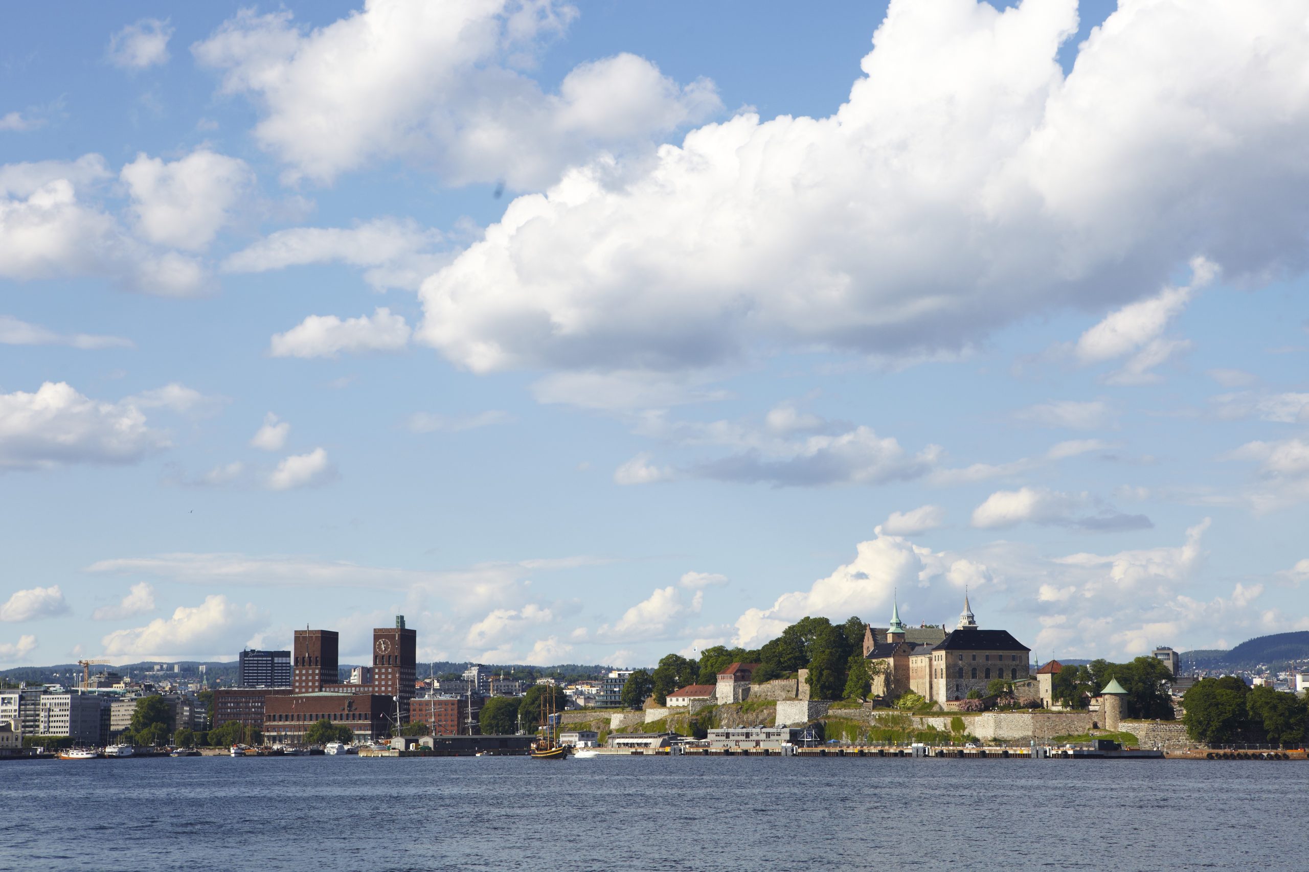 Oslokaia med Oslo Rådhus og Akershus festning kan ses på en fin sommerdag. Bilde tatt fra båt.