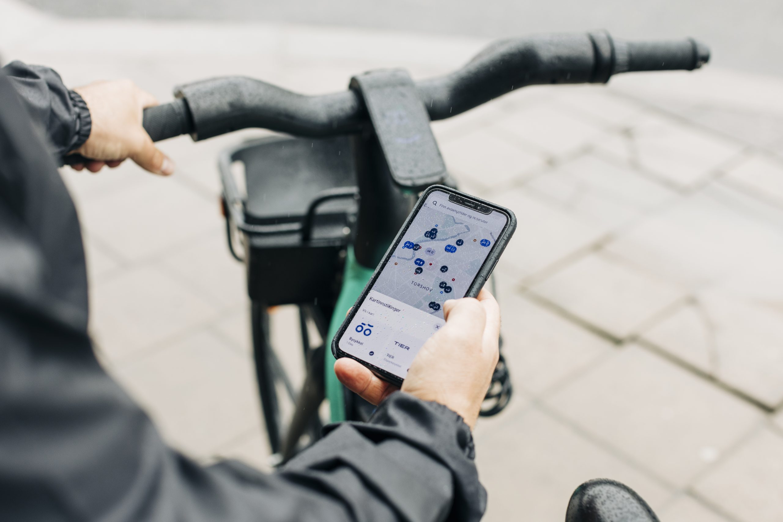Person på sykkel ser på mobiltelefonen sin, som viser kartinnstillinger.