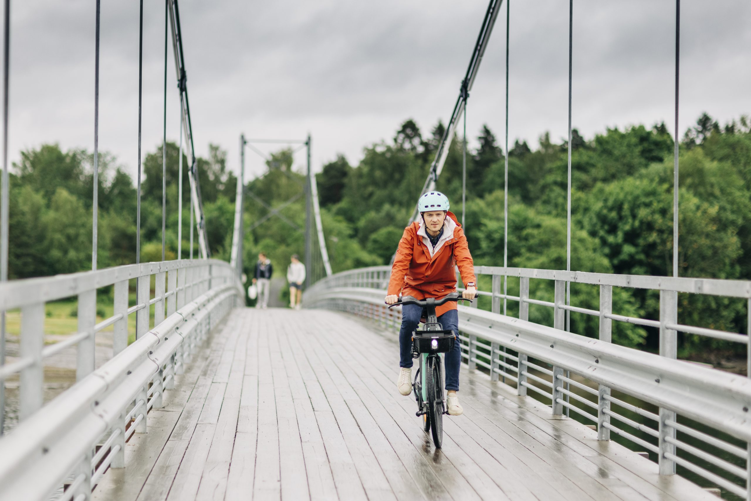 En syklist i regnvær kjører over en bro.