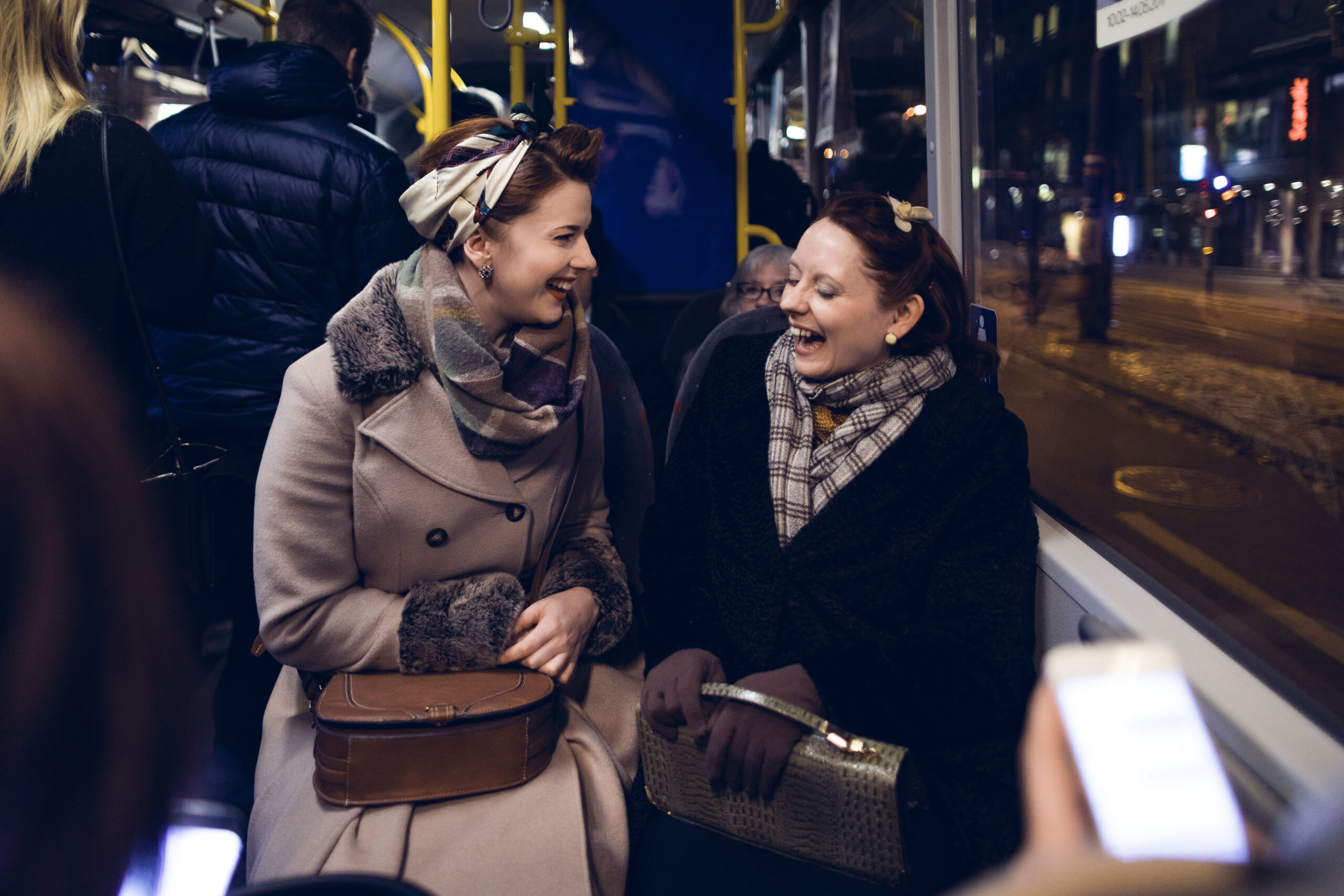 To kvinner sitter og har en morsom samtale på en nattbuss.
