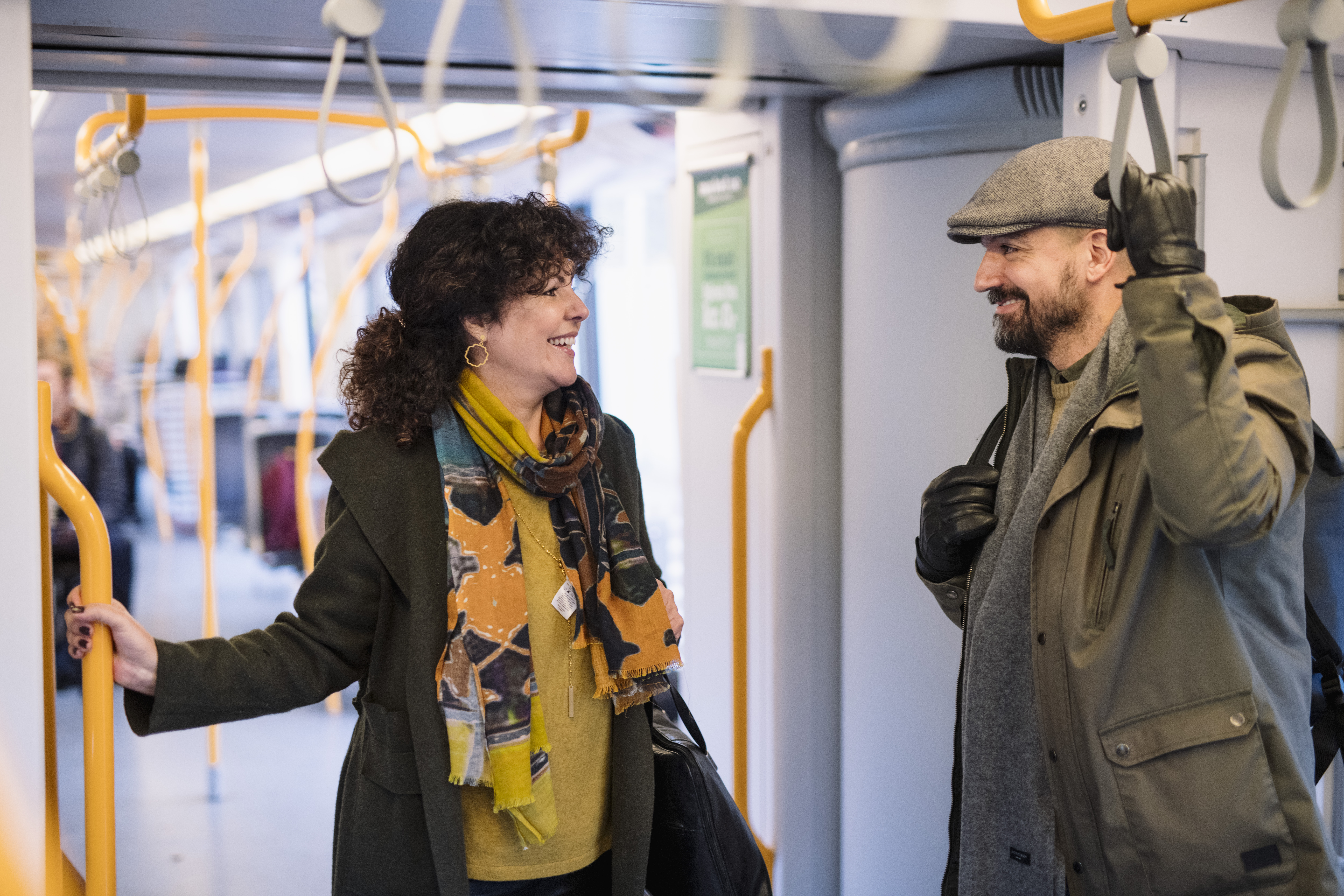 En mann og en kvinne i en hyggelig samtale stående ombord Ruters transportmidler.