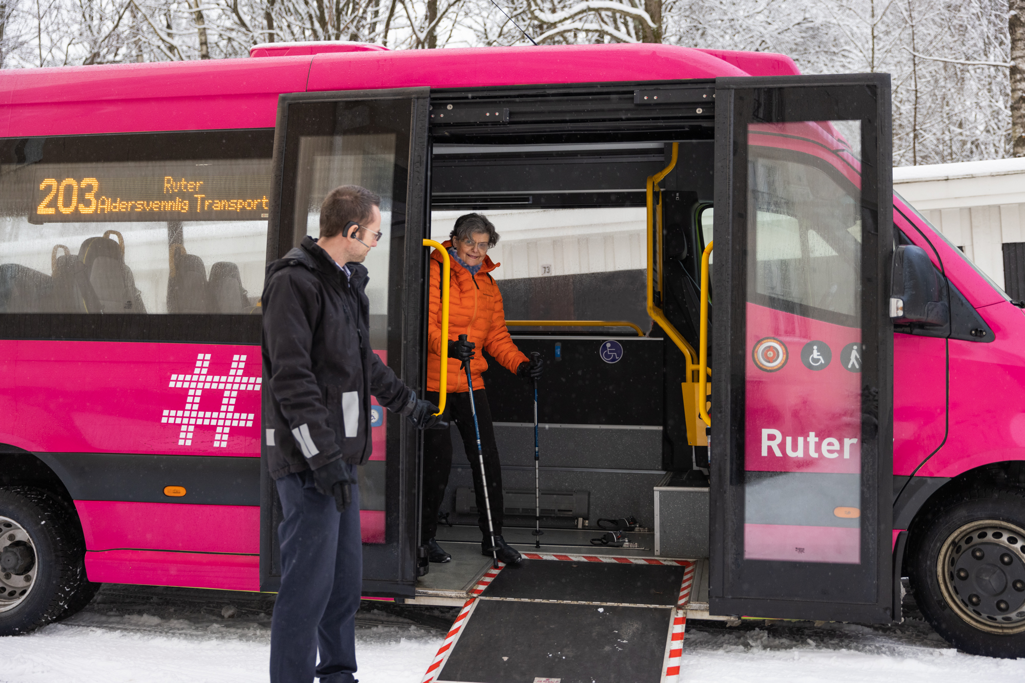 Bestillingstransport for eldre blir tatt i bruk av en kvinne. En mann bistår kvinnen ut.