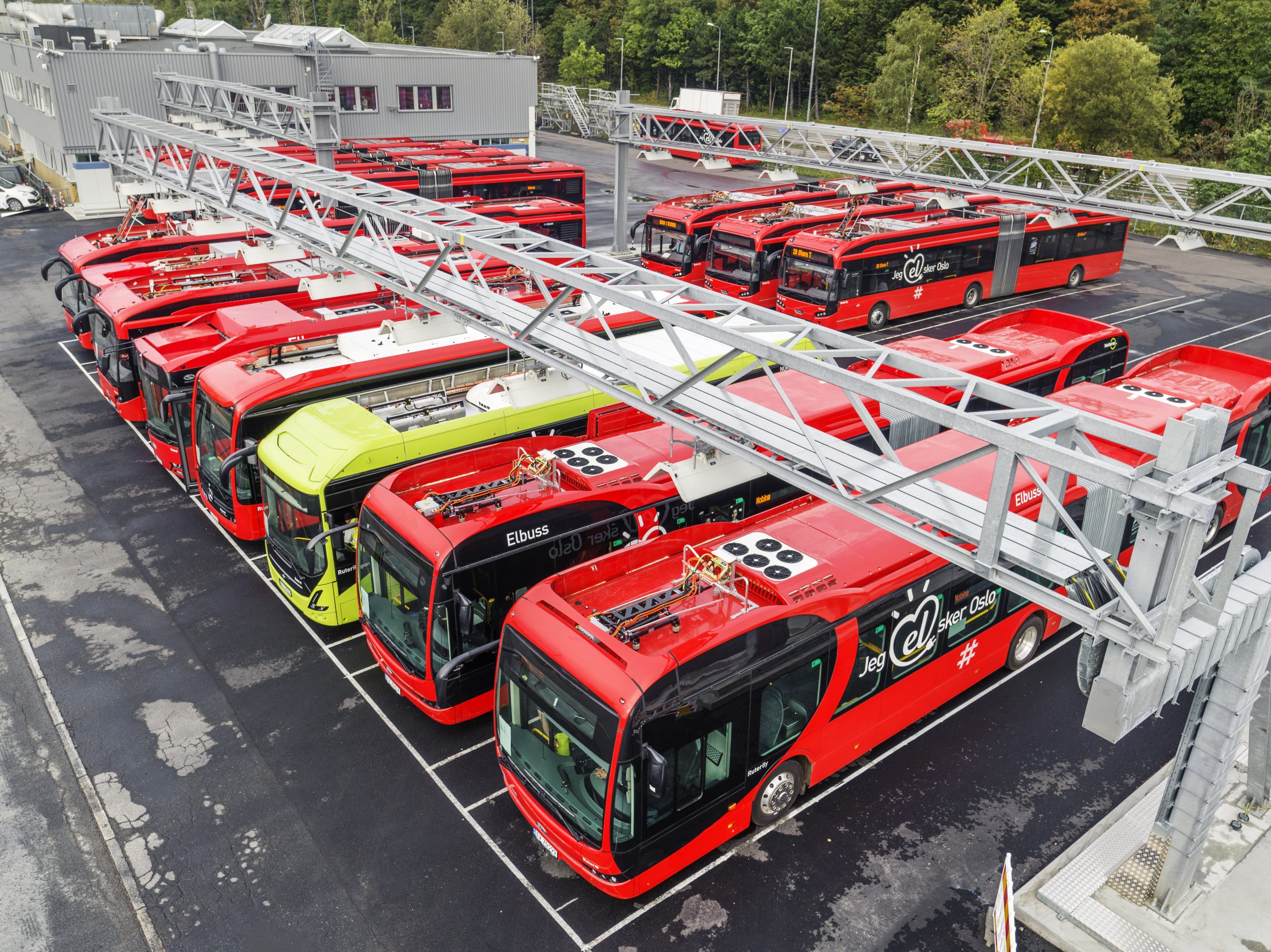 Mange Ruter elbusser lader på en ladestasjon, bilde tatt ovenfra.