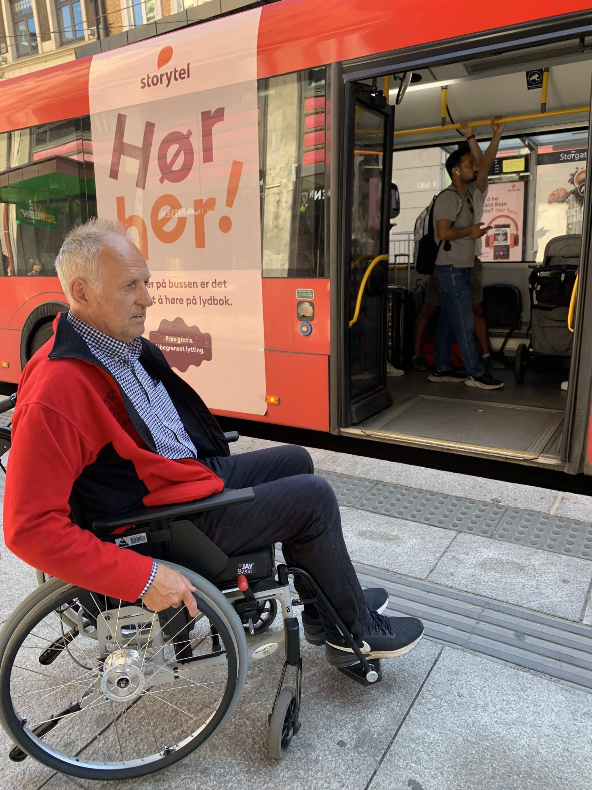 Mann i rullestol venter på å stige på bussen.