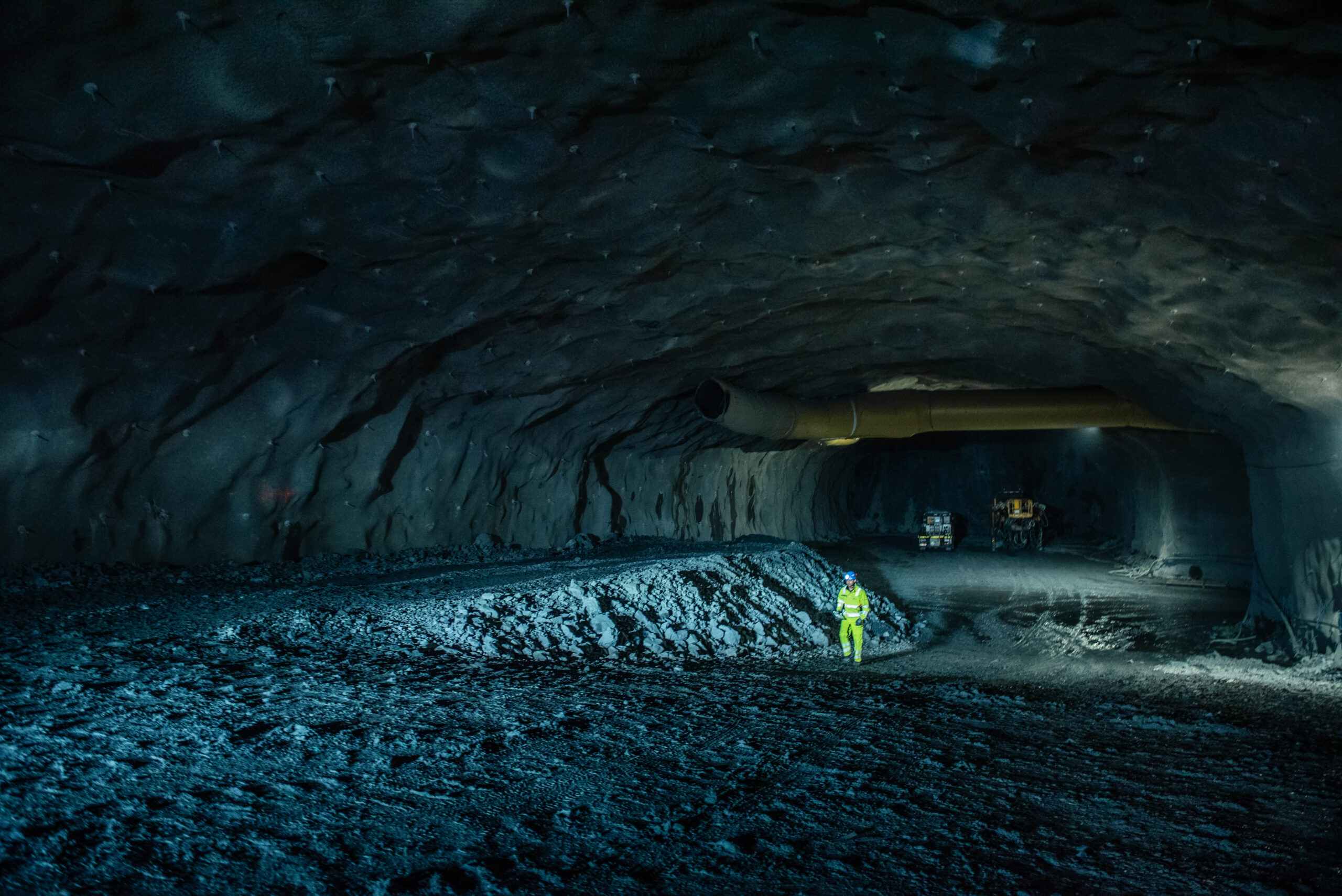 Man in protective gear is shown in a large and dark tunnel.