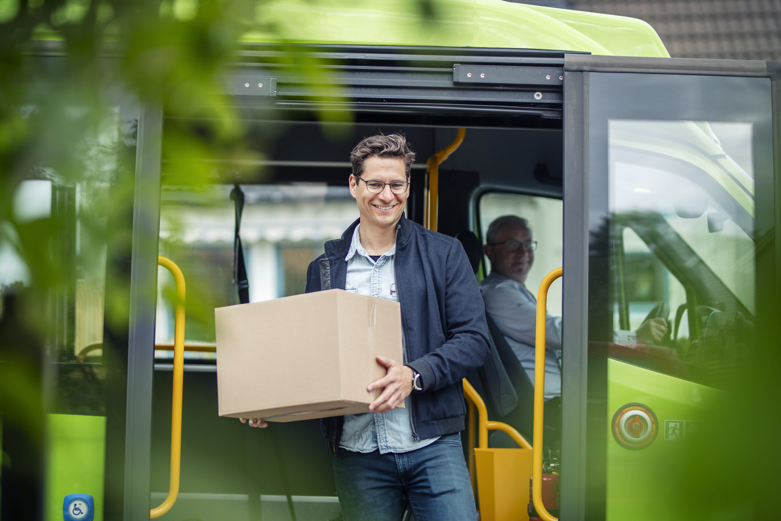 Man with a package gets out of a green Ruter vehicle.