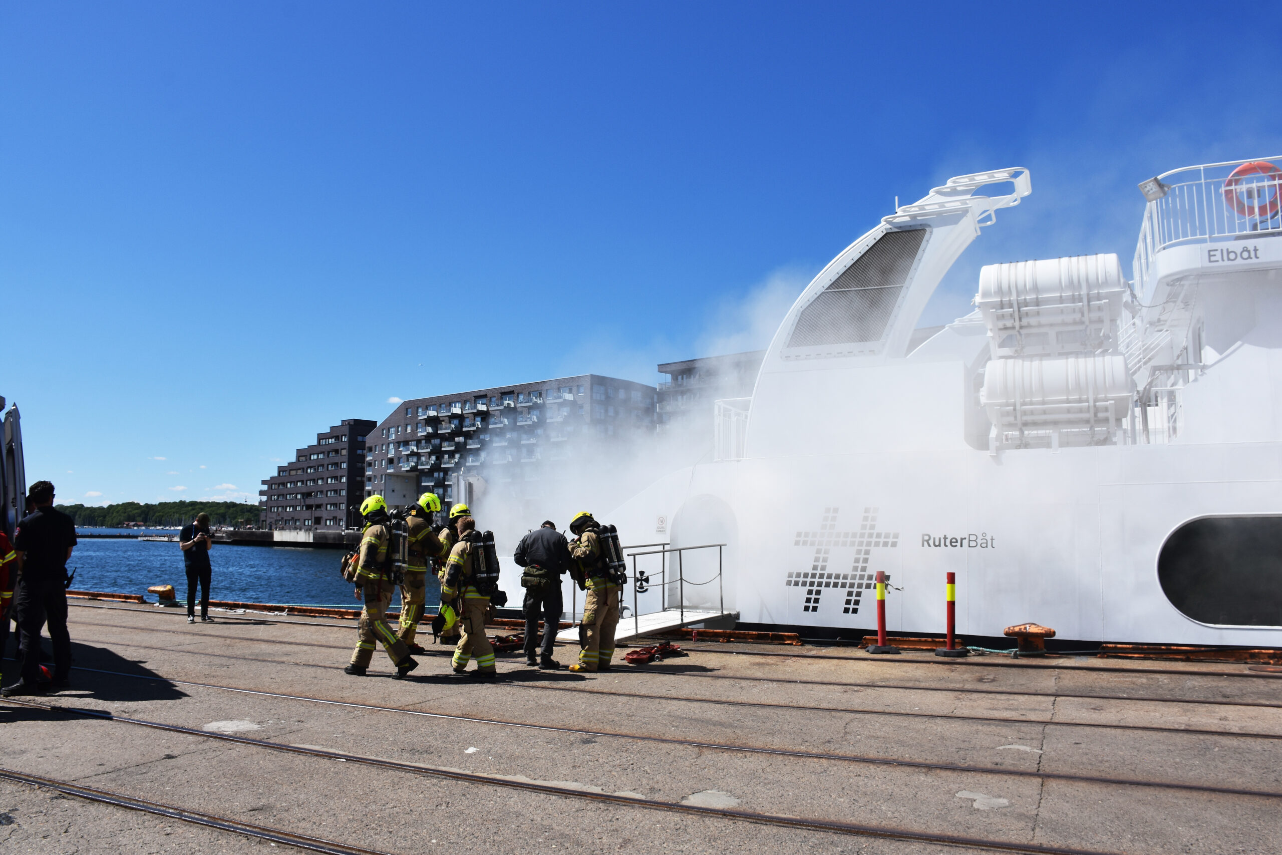 Firefighters practicing in good weather. Water is splashed on a Ruter island ferry.