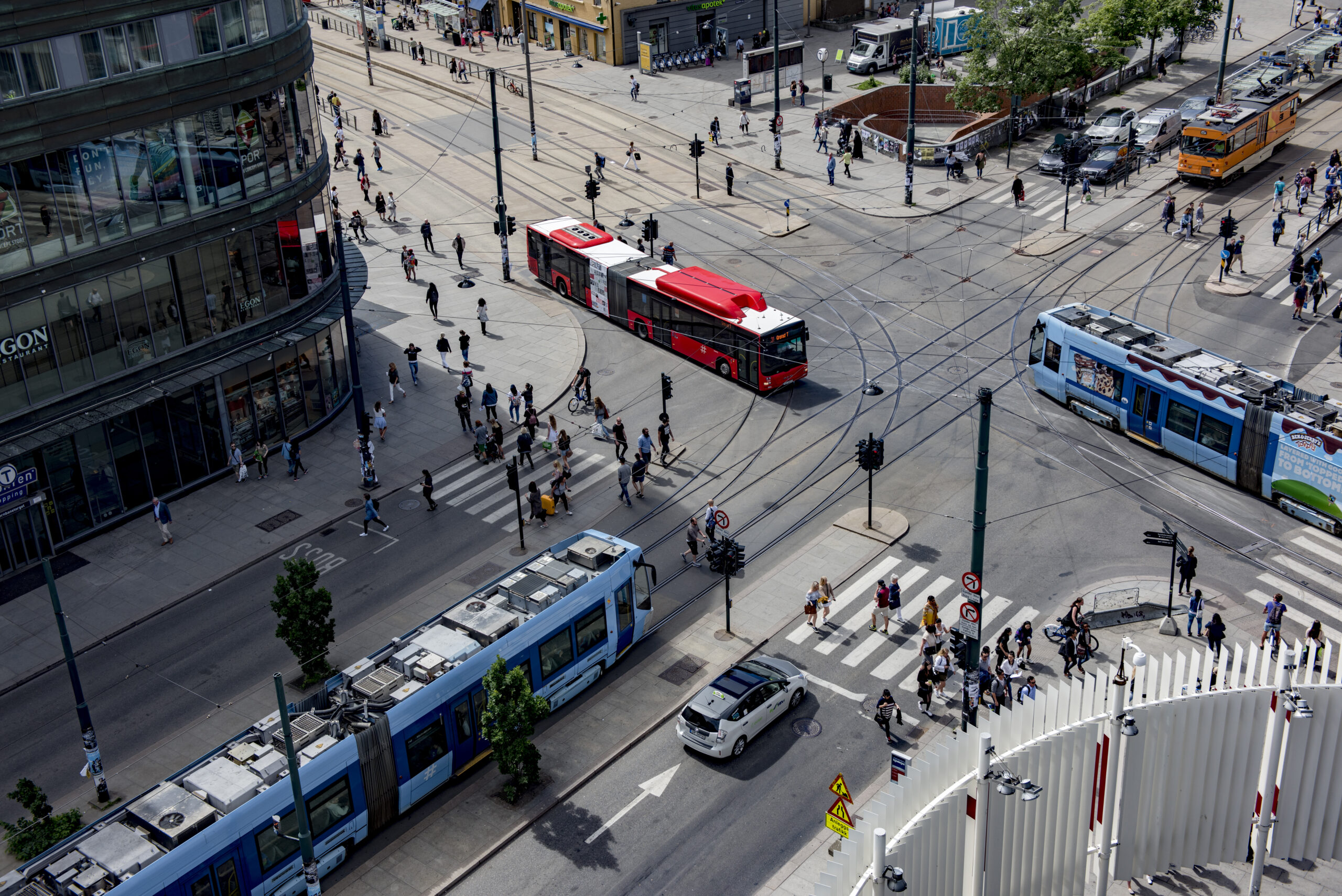 Illustration from above of two trams and a bus running at the intersection at Jernbanetorget.