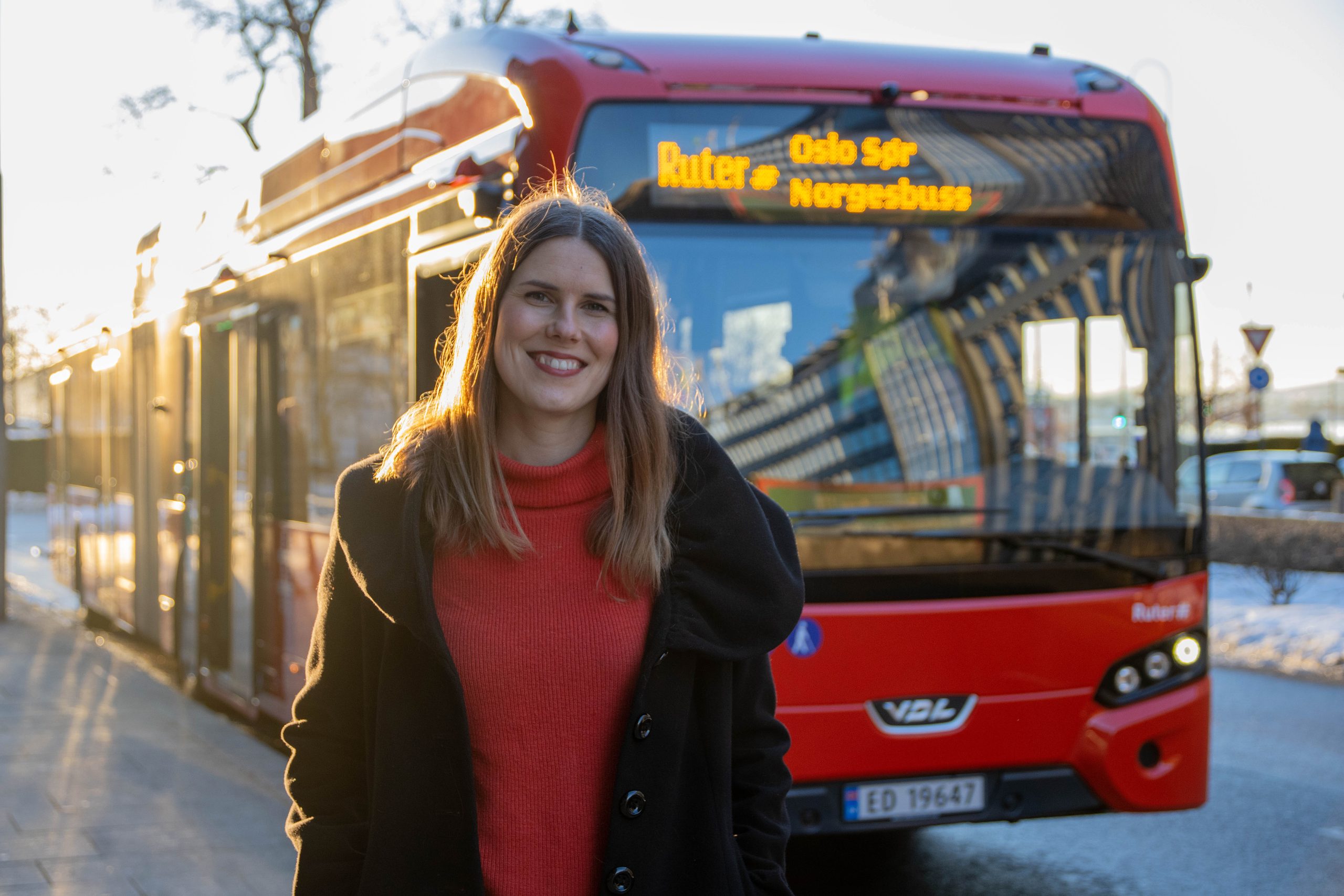 Sirin Stav in front of an electric Ruter city bus.