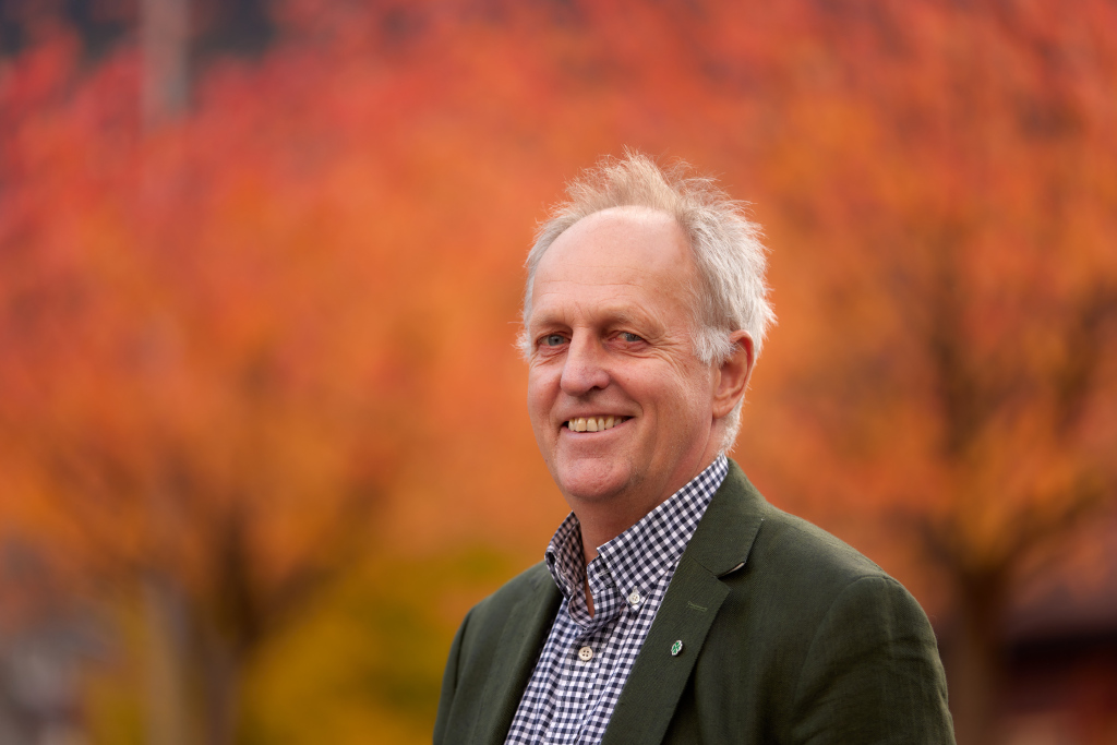 Portrait of Olav Skinnes with a tree in autumn colors in the background.